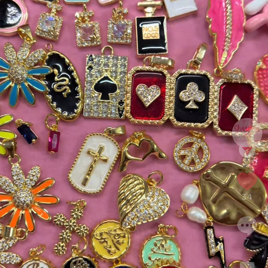 Collection of various jewelry charms on a pink background